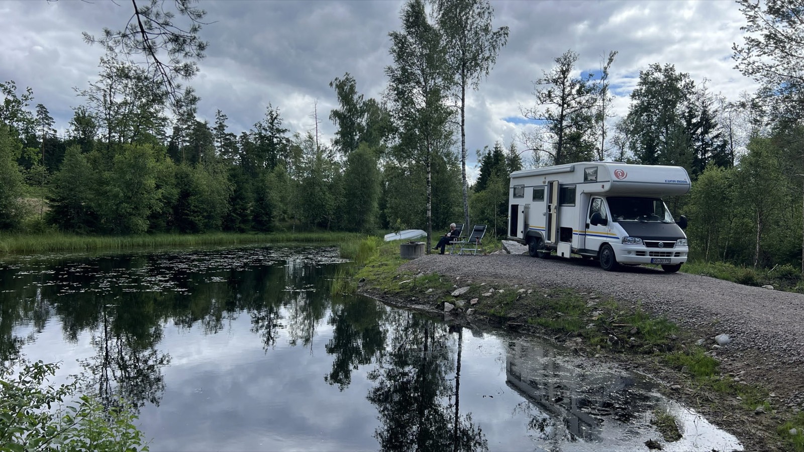 Wohnmobil am Eremit-Stellplatz direkt am See im schwedischen Wald, davor zwei Campingstühle