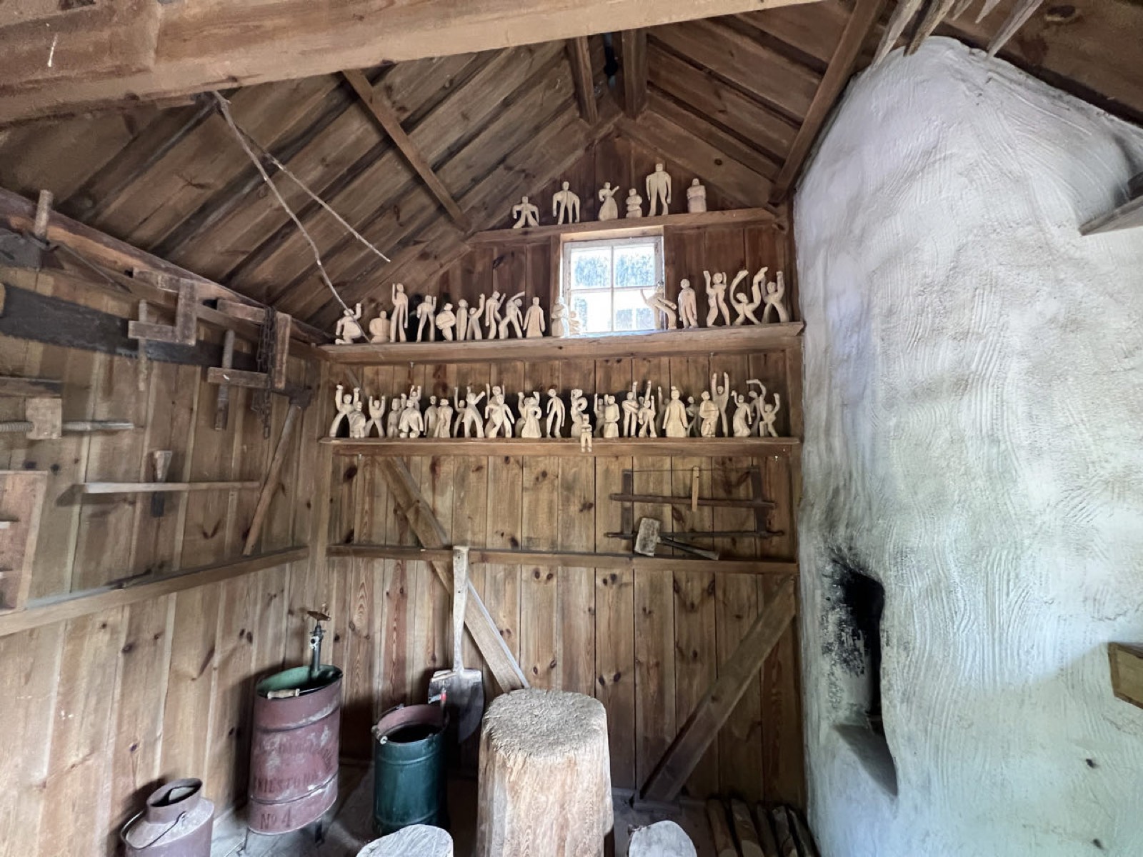 Holzschuppen bei Vimmerby, in den Regalen stehen reihenweise geschnitzte Holzmännchen