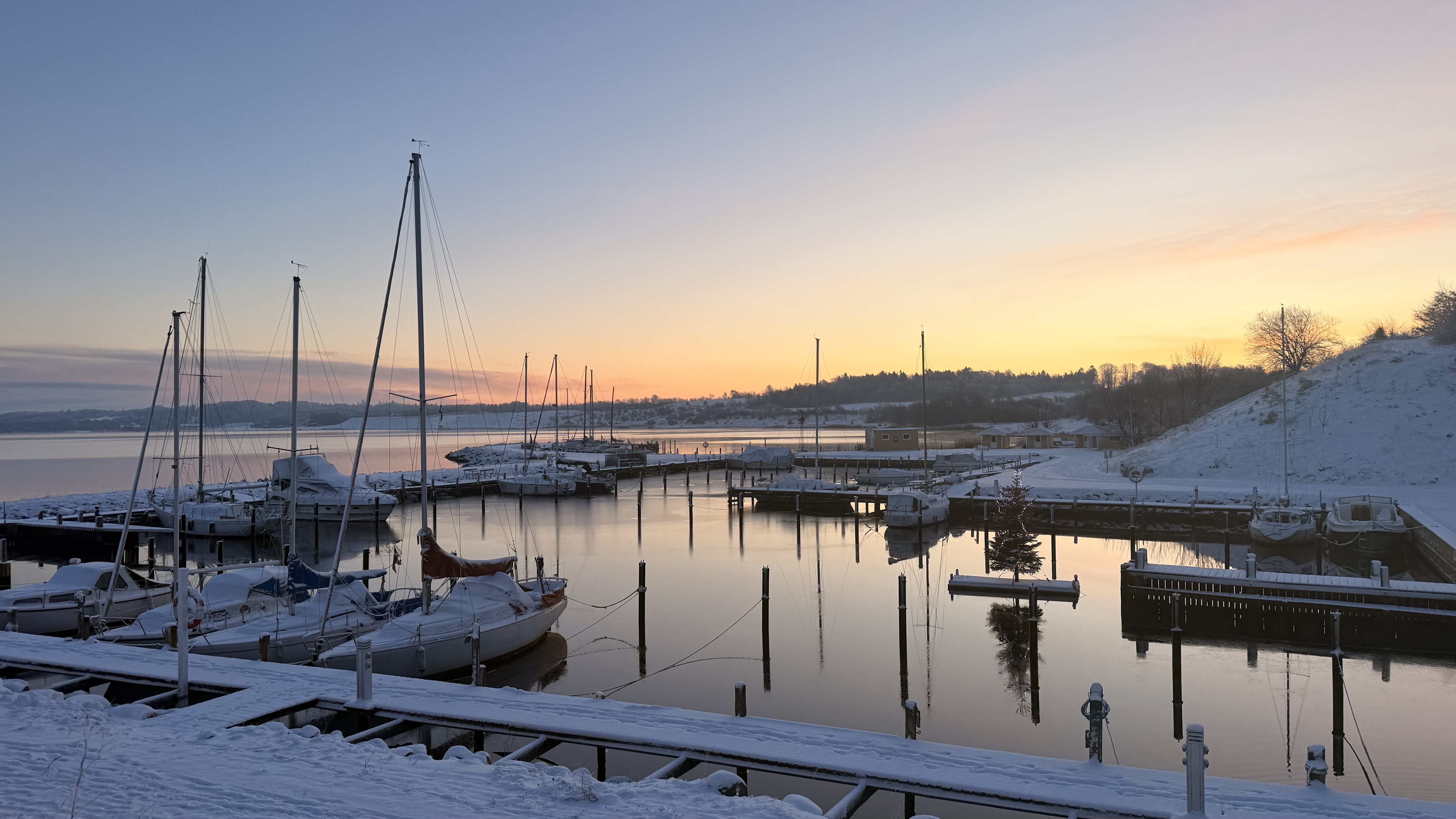 Goldener Sonnenaufgang über der verschneiten Marina in Assens
