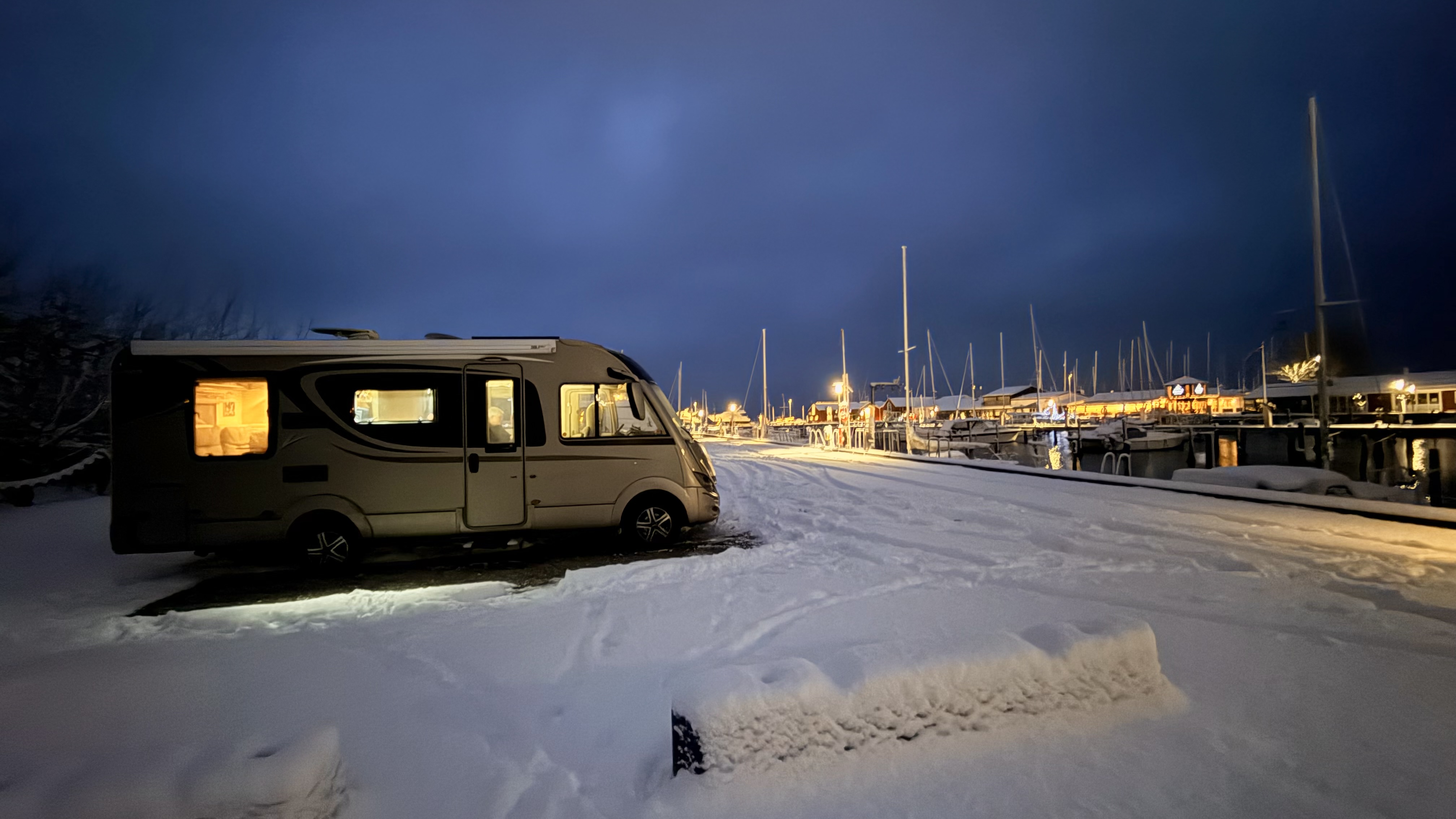 Wohnmobil im Schnee bei Nacht am Hafen Julesminde